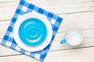 Empty plate, cup and towel over wooden table background