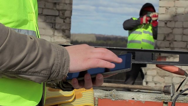 Construction workers with tablet PC and drill at building