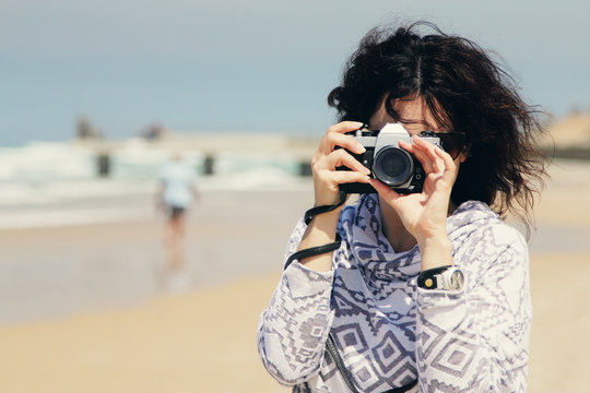 Woman with vintage retro camera having fun on the beach on blue