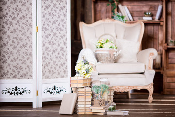 Old books heap, vintage chair and flowers in interior decoration