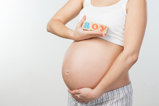 Close up photo of pregnant woman belly and wooden cubes