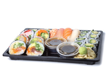 Assorted sushi rolls in a black plastic tray against white backg