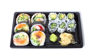 Assorted sushi rolls in a black plastic tray against white backg