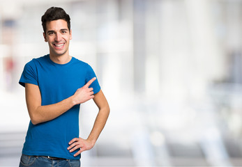 Young man pointing his finger to the copyspace