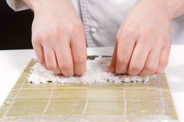 Chef puts rice on a bamboo mat