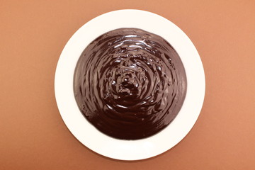 Melted semi-liquid bitter chocolate on a white plate