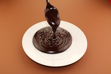 Melted semi-liquid bitter chocolate flowing onto a white plate
