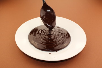 Melted semi-liquid bitter chocolate flowing onto a white plate