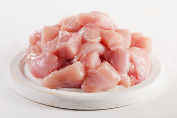Raw chicken meat on  white wooden cutting board.