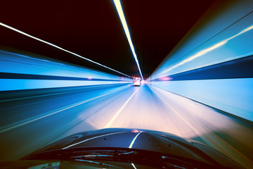 Speeding car inside a highway tunnel exiting to white calm light