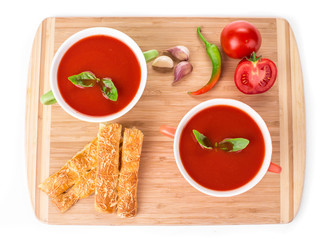 Bowl of tomato soup on wood platter.