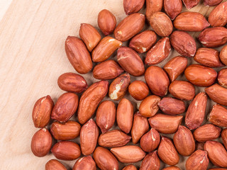 Close up of peanuts on wooden board.
