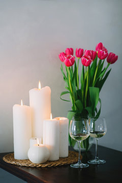  bouquet of pink tulips with candles and two glasses of wine