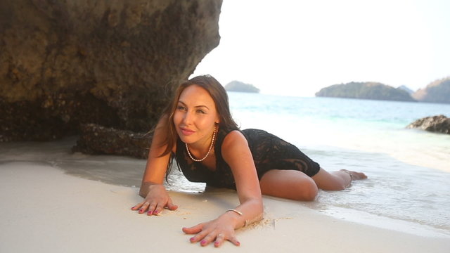 brunette girl half dressed in lace frock lies on sand	
