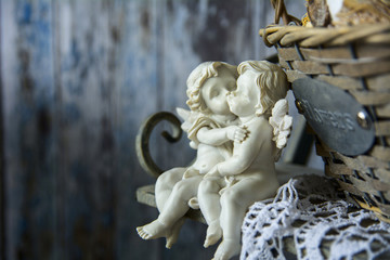 Figurines angels sitting on a bench near the wicker basket