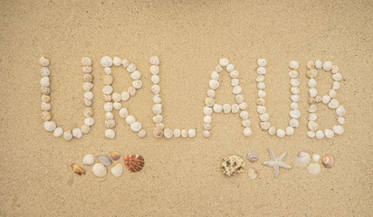 Wort URLAUB aus Schneckenhäuschen am Sandstrand