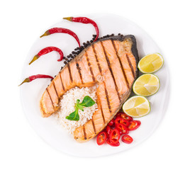 Grilled salmon steak with vegetables on plate.