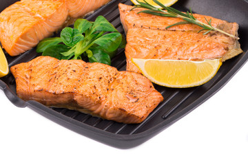 Fried salmon fillet in pan with lemon.