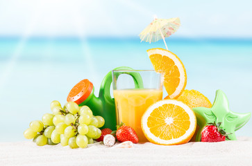     Fresh orange juice, fruits on sand with blue sky background