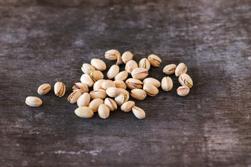 Heap of pistachio nuts, close up on wooden table background