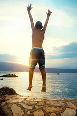 Fototapeta na wymiar boy jumping and taking a deep breath at the sunset