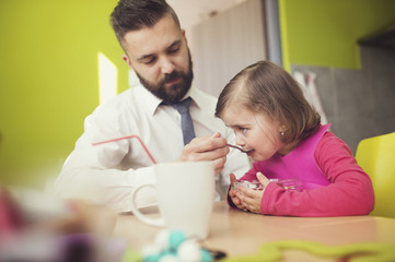 Obraz na płótnie Canvas Young father feeding his little daughter 