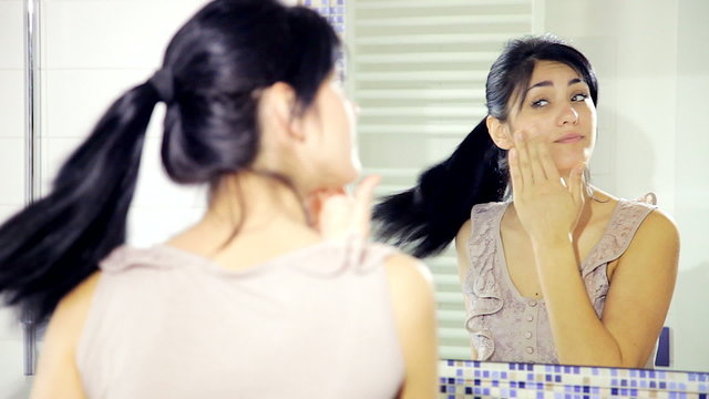 Woman in front of mirror putting makeup medium shot