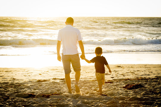 happy father with son walking on beach sunset summer holidays
