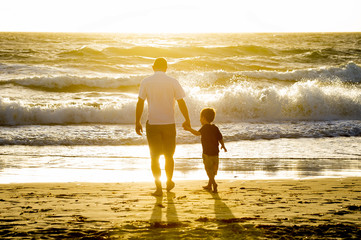 happy father with son walking on beach sunset summer holidays