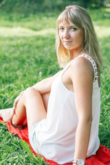 Fototapeta na wymiar Young woman sits on green grass