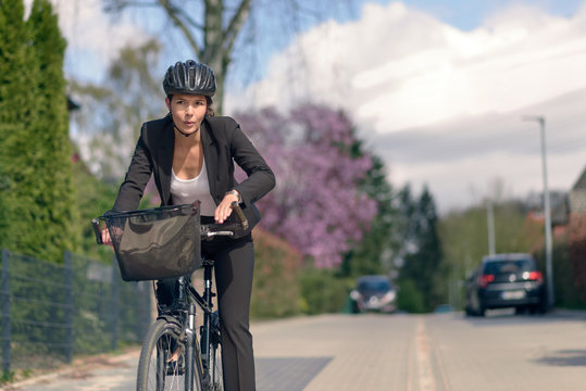 Gesch&auml;ftsfrau auf ihrem Fahrrad ist unter Zeitdruck