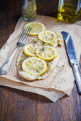 Baked fish with lemon and spices on a baking paper