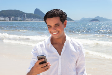 Junger Mann bekommt eine SMS an der Copacabana