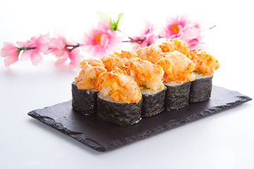 Spicy sushi roll on a stone plate over white background