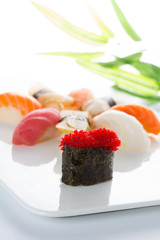 Sushi gunkan with red tobiko and nigiri on a white plate