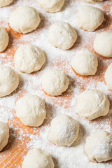 Small balls of fresh homemade dough on floured wooden board