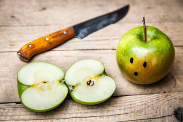 Knife slice apple on wooden background.