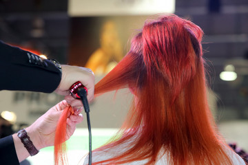 Hairdresser turns hair curling iron of young girl