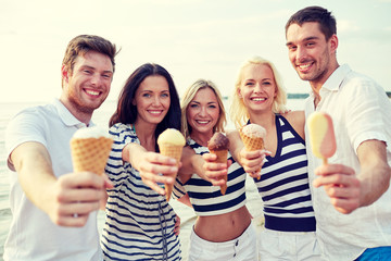 Obraz premium smiling friends eating ice cream on beach
