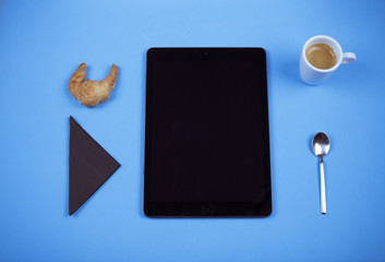 Breakfast with croissant, coffee and tablet.