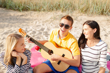 Fototapeta na wymiar group of happy friends playing guitar on beach