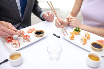 close up of couple eating sushi at restaurant