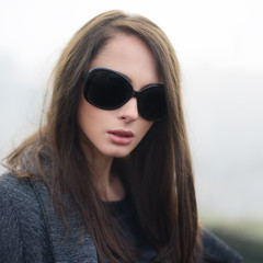portrait of a beautiful brunette wearing sunglasses in winter