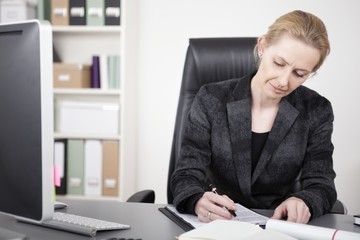 Adult Businesswoman Writing on Top of her Desk