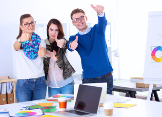 Young business people standing at office near desk and showing