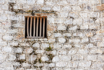 Prison cell window with wooden bars in a white brick wall