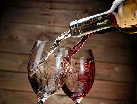 Red and white wine pouring on wood background