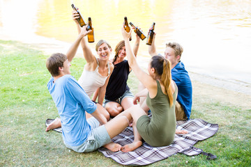 Freunde sitzen in Runde trinken Bier am See