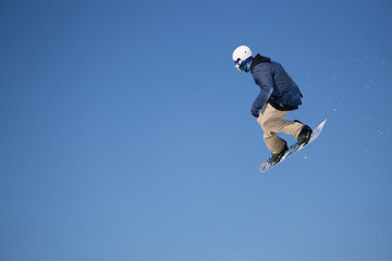 Fototapeta na wymiar Snowboarder jumps in Snow Park