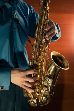 Man playing jazz saxophone closeup. Golden sax.